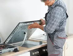 Appliance repair technician installing a built-in cooktop in Santa Ana, CA
