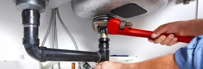 Garbage disposal repair technician tightening the sink drain and disposal connection in Santa Ana, CA