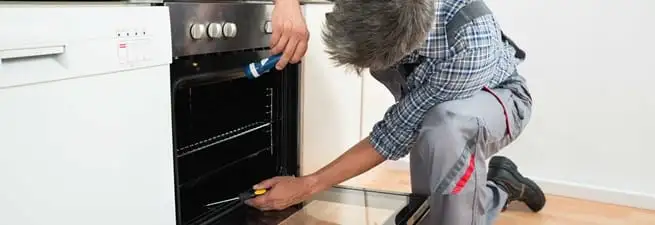 Oven repair technician inspecting and servicing an electric oven in Santa Ana, CA
