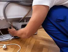 Appliance repair technician fixing refrigerator water line and connections in Santa Ana, CA