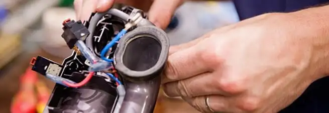 Vacuum repair technician reconnecting wiring and components in Santa Ana, CA