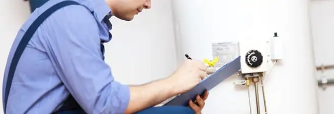 Water heater repair technician inspecting the unit and recording service notes in Santa Ana, CA