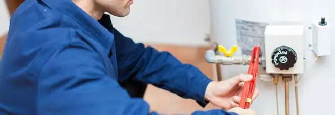Water heater repair technician adjusting the temperature control and gas valve in Santa Ana, CA